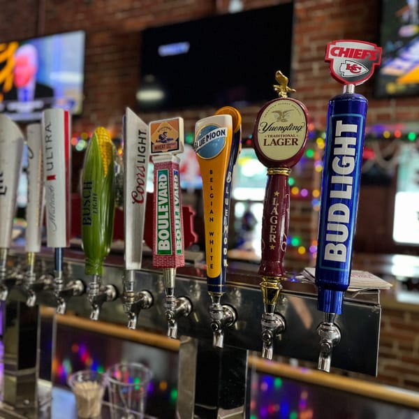 Close-up of beer taps at Emerson Biggins sports bar, featuring various brands and a Chiefs tap.