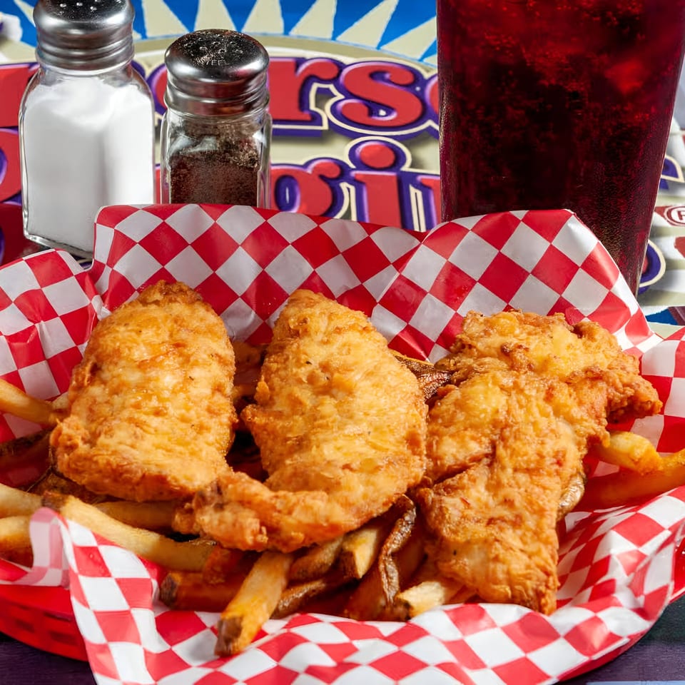 Emerson Biggins' fried chicken tenders and fries in a red checkered basket with a drink.