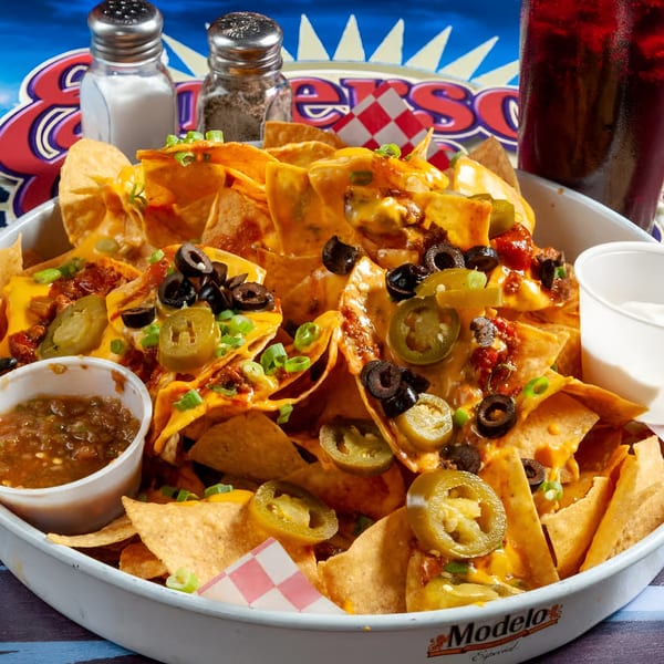 A large platter of Emerson Biggins nachos with cheese, meat, olives, jalapeños, and green onions.