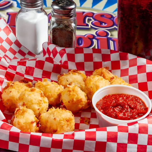 Golden-fried cheese curds with a side of marinara sauce in a red and white checkered basket.